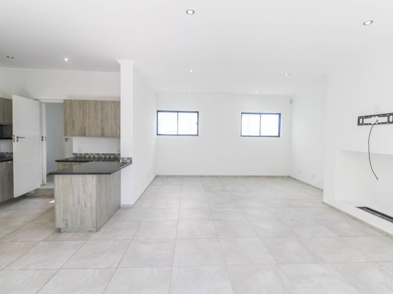 Spacious open-plan living area featuring tiled floors, recessed lighting, a built-in fireplace, and a modern kitchen with granite countertops and ample cabinetry.