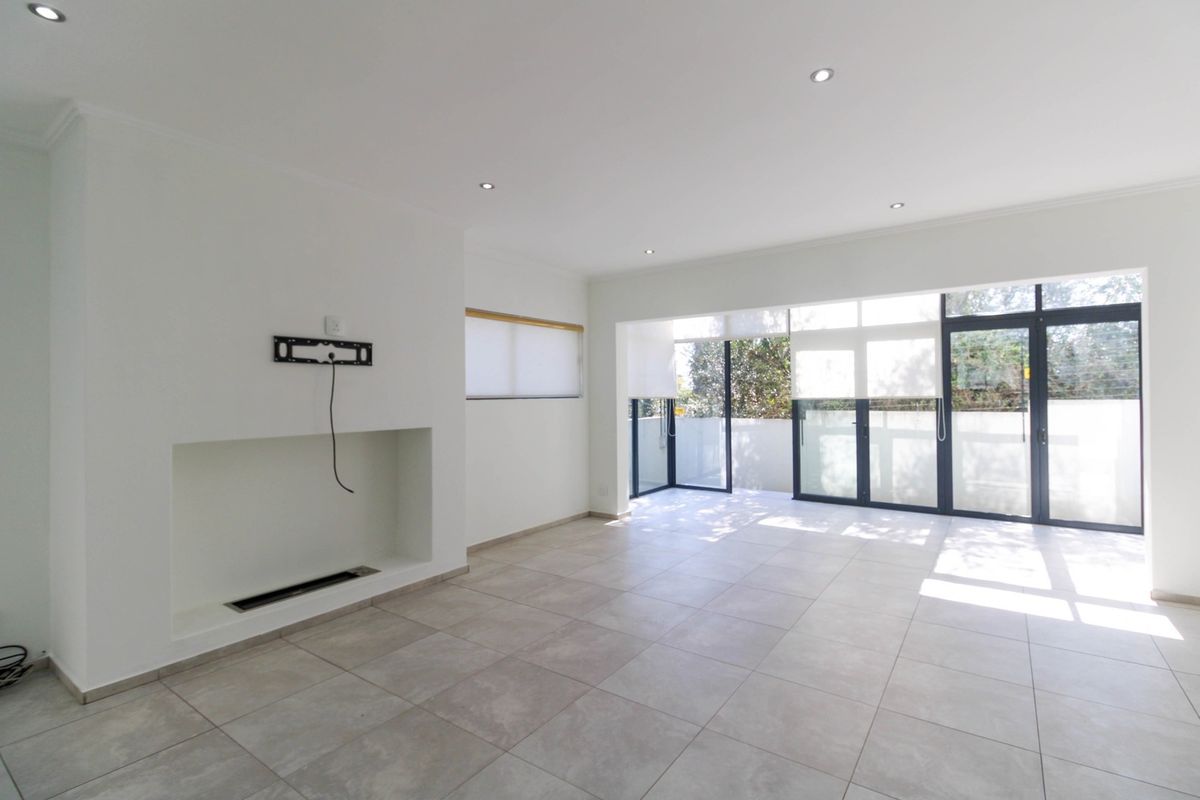 Spacious, light-filled living area featuring neutral tiled flooring, a built-in fireplace, and large aluminium sliding doors opening to an outdoor space.