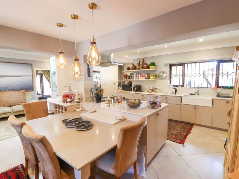 Spacious open-plan kitchen and dining area featuring a central island, farmhouse sink, modern cabinetry, and elegant pendant lighting.