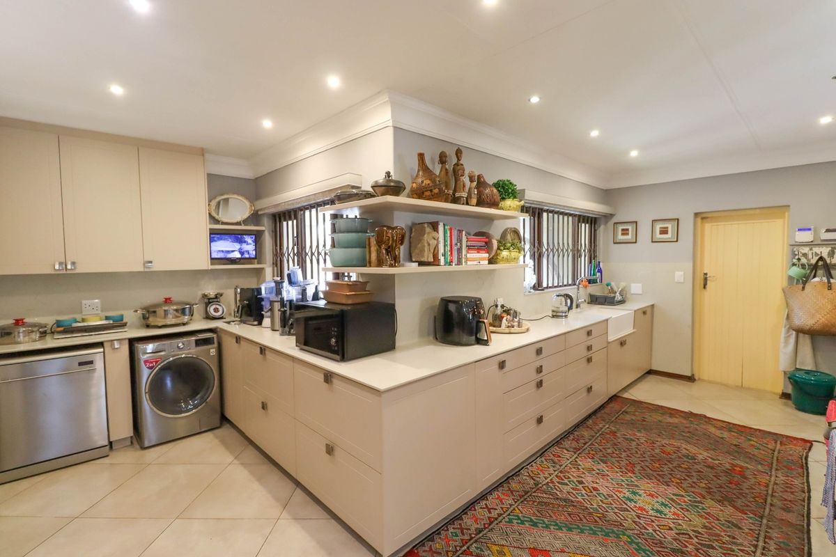 A well-maintained kitchen featuring neutral cabinetry, quartz countertops, a farmhouse sink, and recessed lighting, offering a functional and clean workspace.