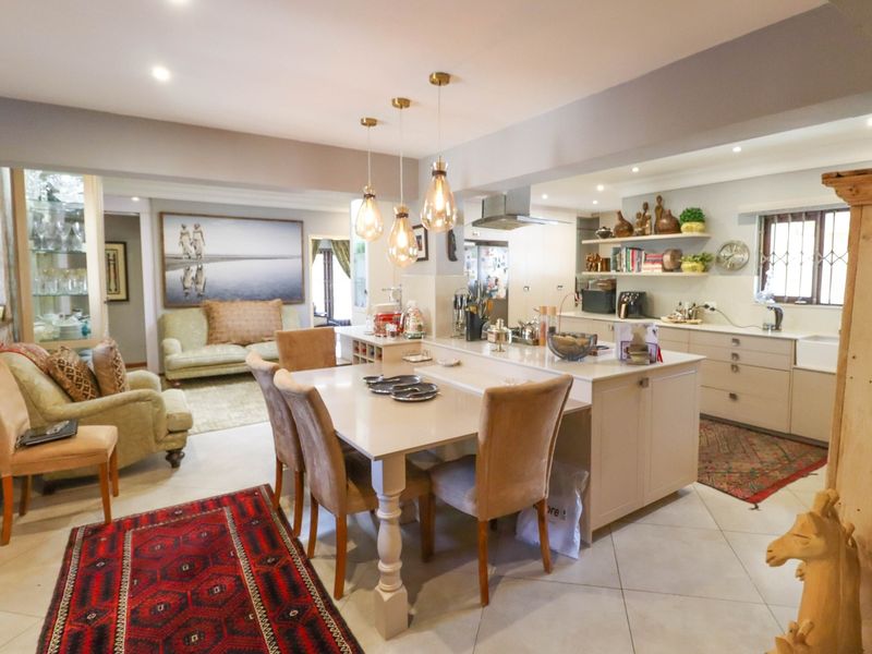 Spacious open-plan kitchen and dining area featuring a central island, modern cabinetry, and integrated lighting, creating a functional and inviting living space.
