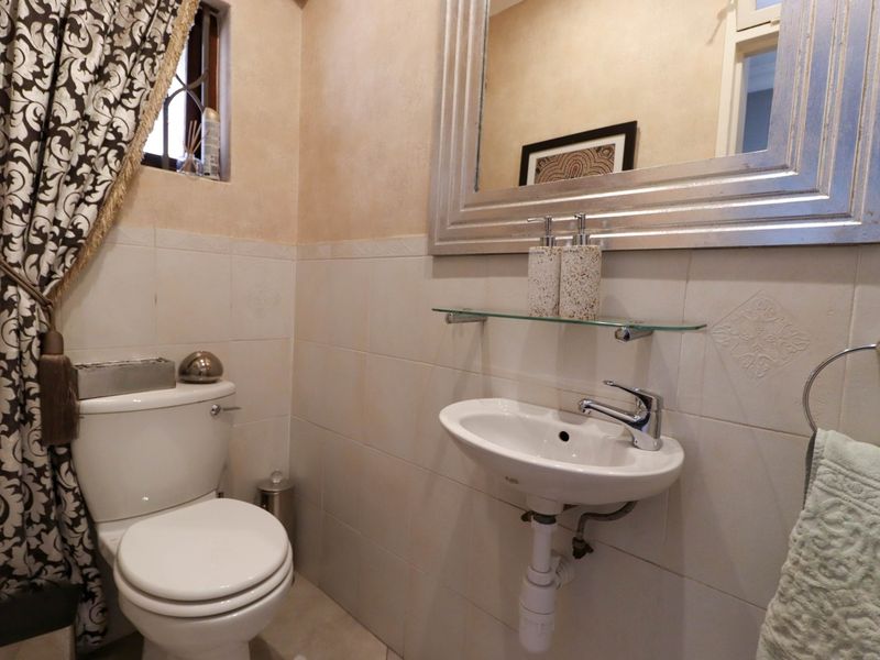 A compact bathroom featuring a wall-mounted basin with chrome mixer tap, a standard toilet, and tiled wall finishes.
