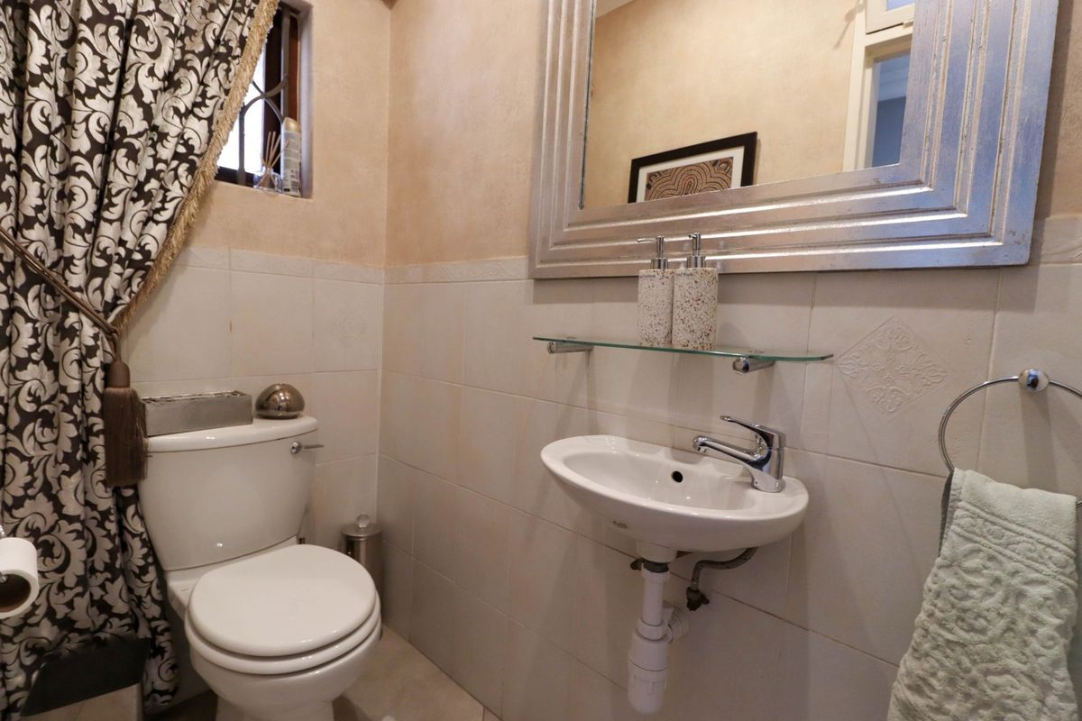 A compact bathroom featuring a wall-mounted basin with chrome mixer tap, a standard toilet, and tiled wall finishes.