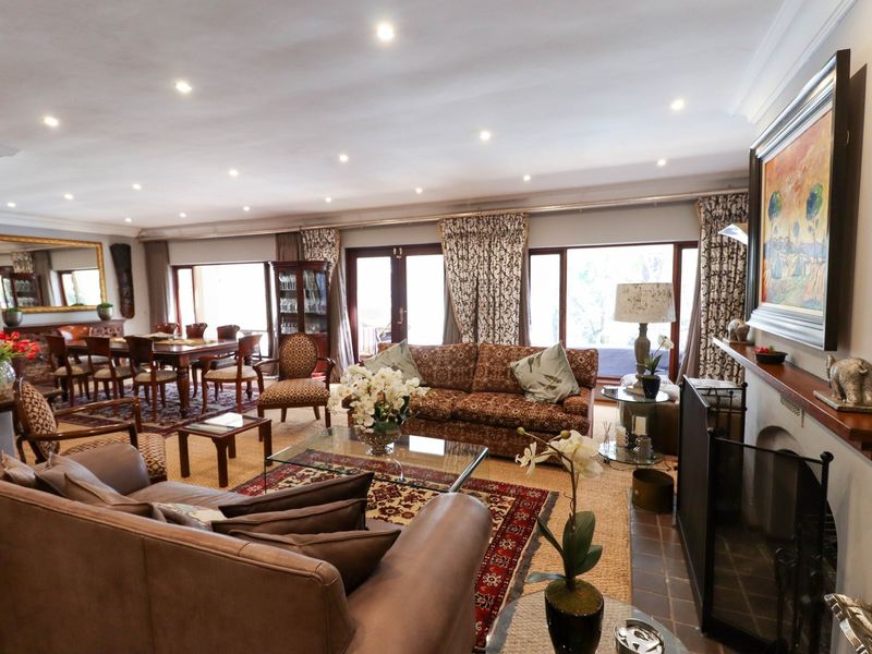 Spacious open-plan living and dining area featuring a fireplace with timber mantelpiece, recessed downlights, and large sliding glass doors providing natural light.