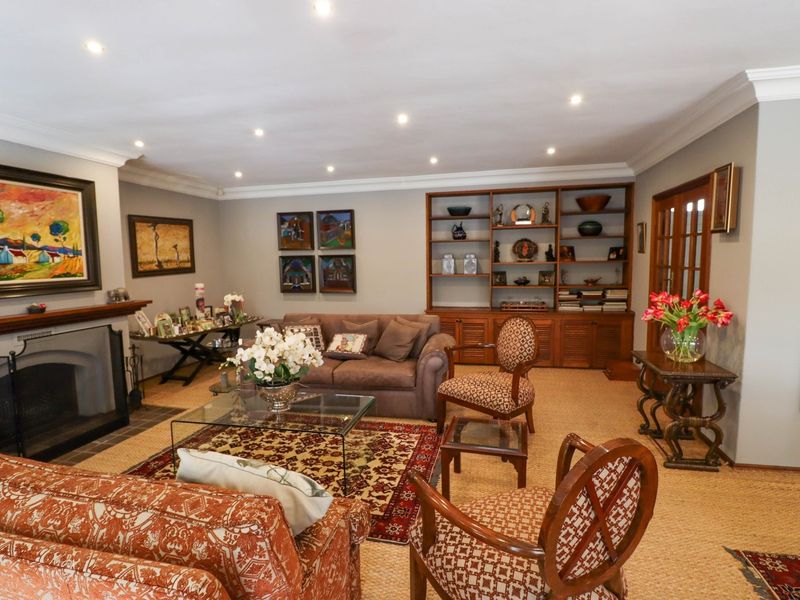 A well-maintained living room featuring a fireplace, built-in wooden shelving, recessed lighting, and classic french doors.