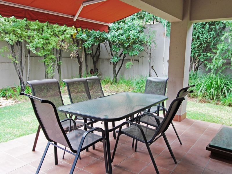 Covered patio area featuring tiled flooring, a retractable awning, and direct access to a private garden space.