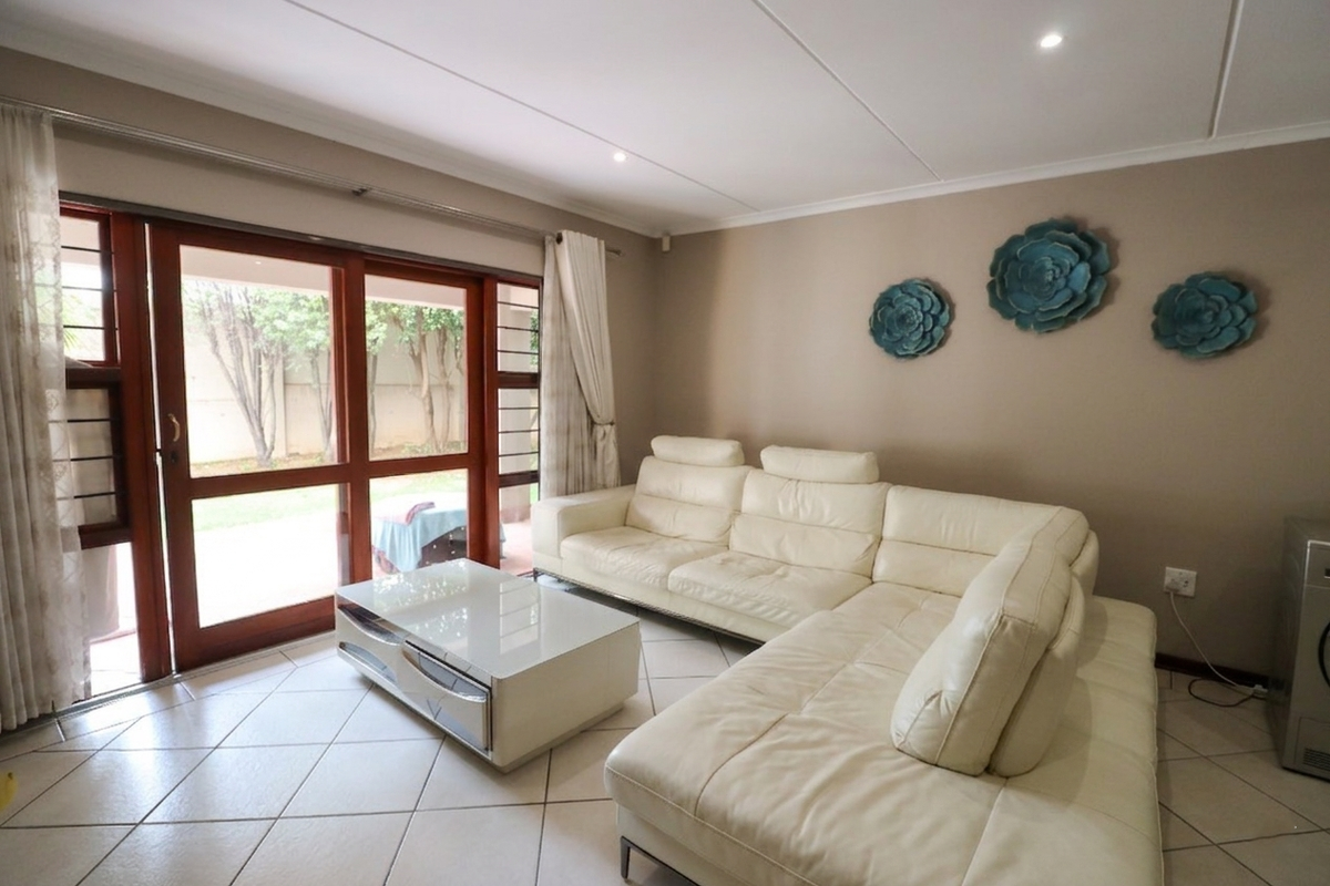 A bright living room featuring tiled flooring, recessed downlights, and a large sliding glass door providing direct access to the outdoor area.