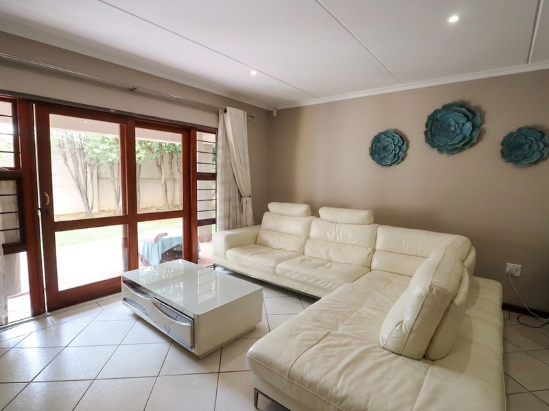 A bright living room featuring tiled flooring, recessed downlights, and a large sliding glass door providing direct access to the outdoor area.