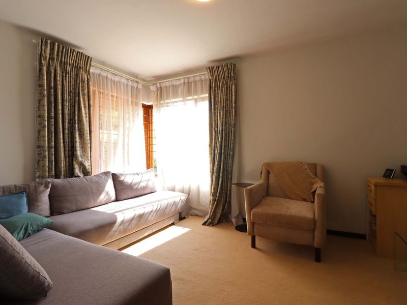 A comfortable living room featuring carpeted flooring and large corner windows that allow for ample natural light.