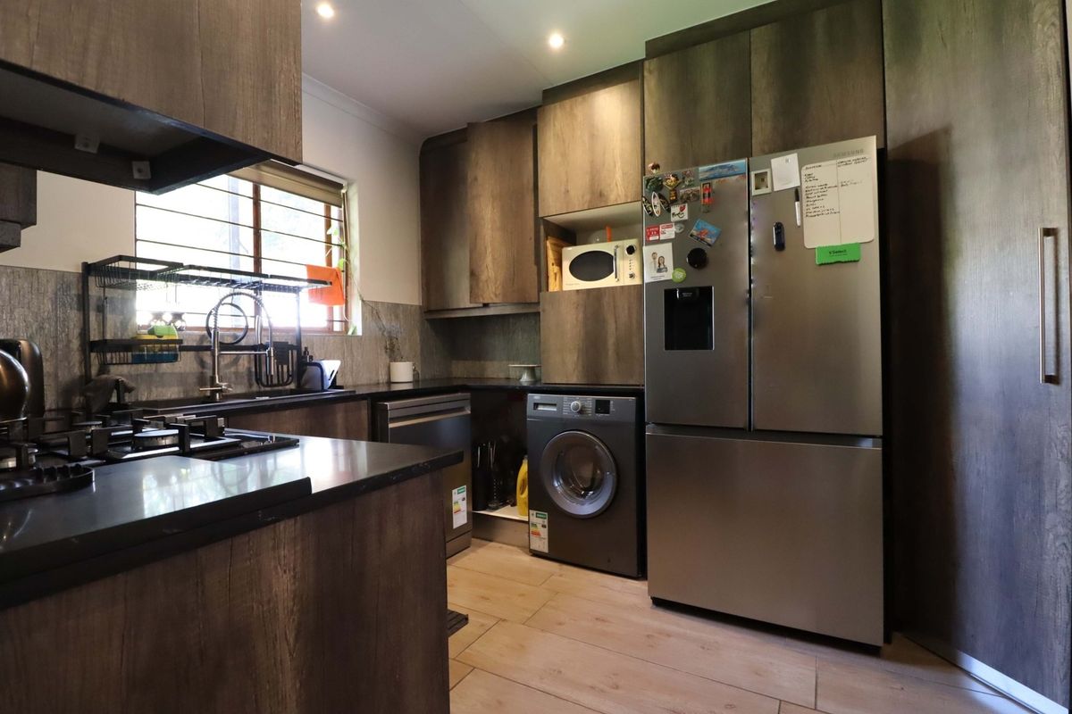 Modern kitchen featuring dark wood-look cabinetry, stone countertops, gas hob, and integrated appliance spaces with recessed lighting and tiled flooring.
