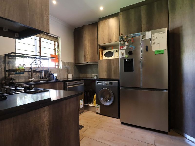 Modern kitchen featuring dark wood-look cabinetry, stone countertops, gas hob, and integrated appliance spaces with recessed lighting and tiled flooring.
