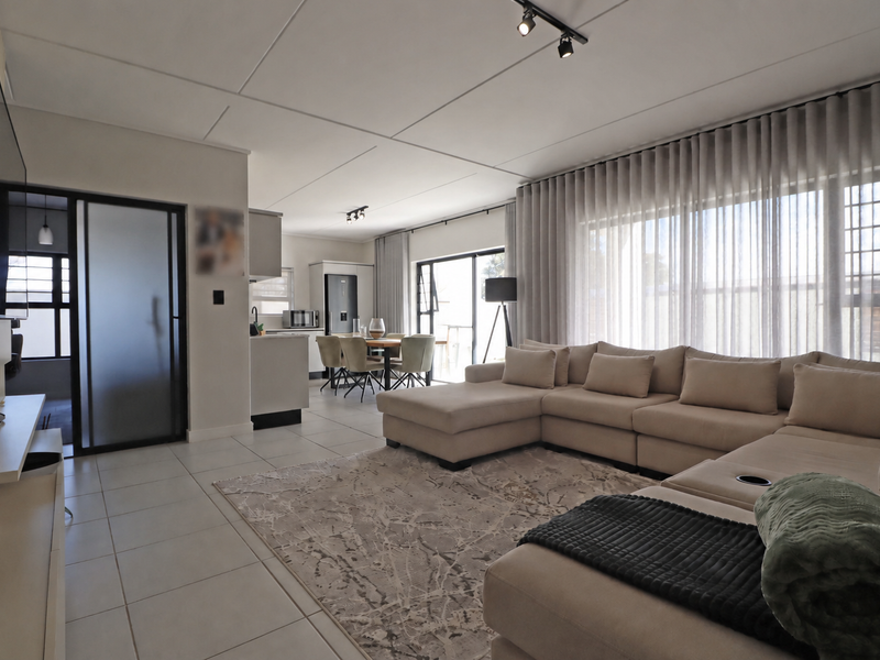 Spacious open-plan living and dining area featuring modern tiled floors, track lighting, and seamless access to the outdoor patio through large sliding glass doors.