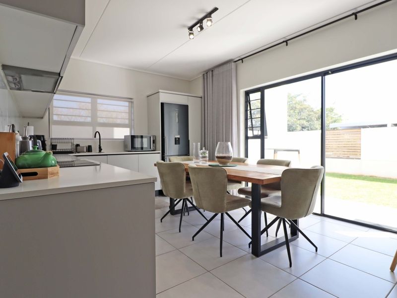 Modern open-plan kitchen and dining area featuring sleek cabinetry, stone countertops, and large sliding glass doors providing seamless access to the outdoor space.