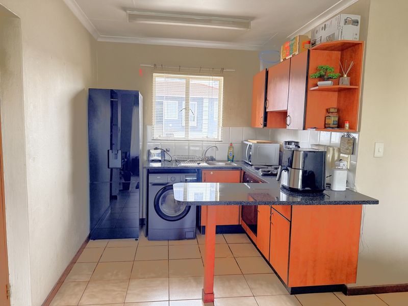 A functional kitchen featuring orange cabinetry, granite countertops, tiled backsplash, and integrated appliances, offering a practical layout for daily use.