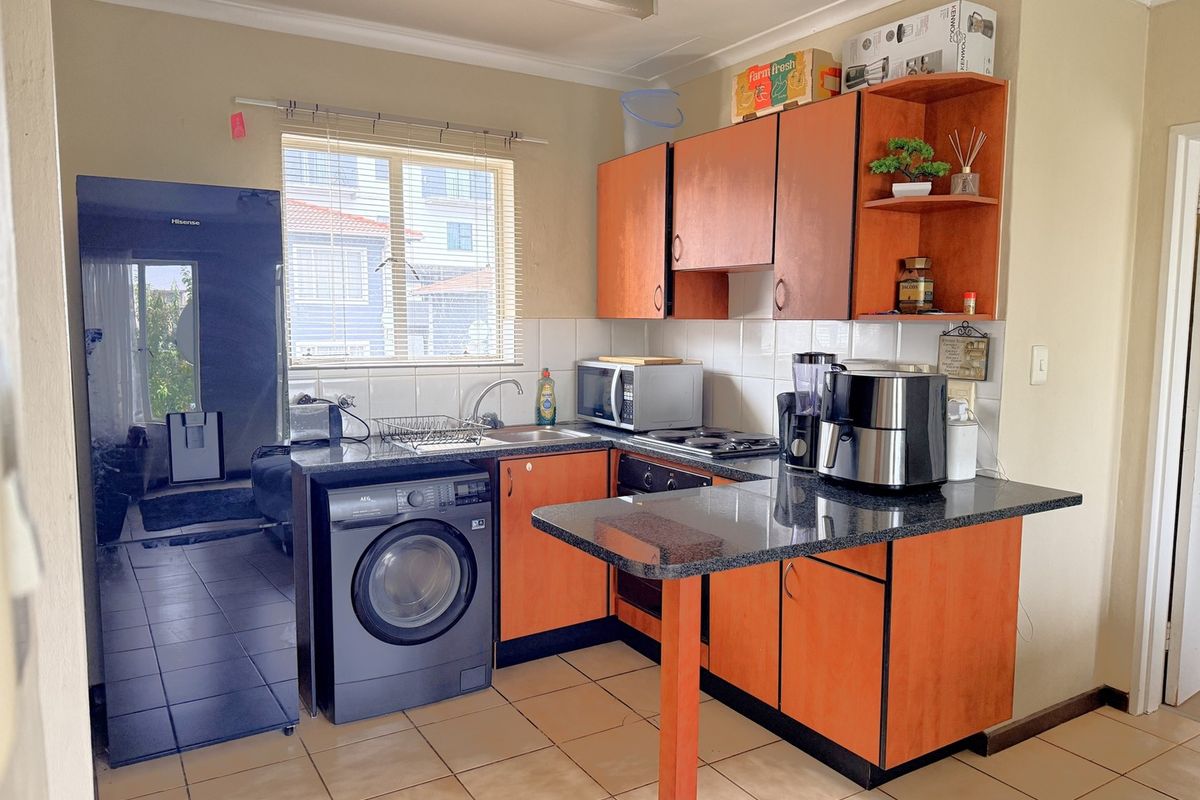 Functional kitchen featuring laminate cabinetry, granite countertops, built-in oven, hob, and tiled flooring, offering a practical layout for daily meal preparation.