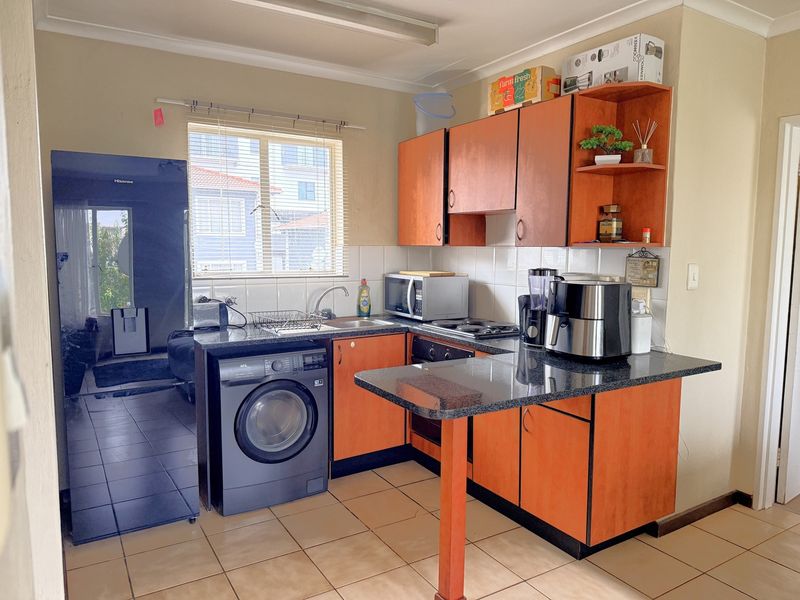 Functional kitchen featuring laminate cabinetry, granite countertops, built-in oven, hob, and tiled flooring, offering a practical layout for daily meal preparation.