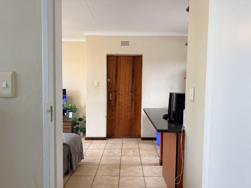 Open plan living area featuring tiled flooring, a granite breakfast bar, and a wooden interior door.