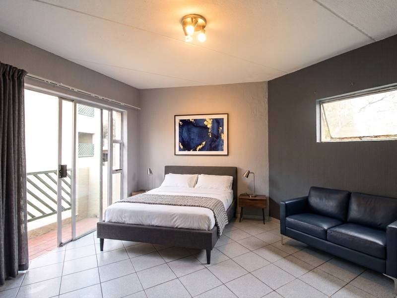 Spacious bedroom featuring tiled flooring, a ceiling light fixture, and a sliding glass door providing access to an outdoor balcony area.