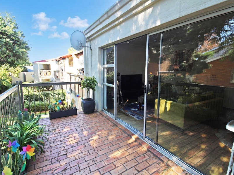 A private balcony featuring brick paving and a metal balustrade, providing seamless indoor-outdoor flow through large sliding glass doors.