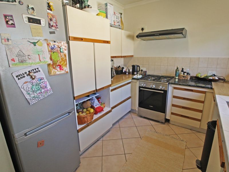 A functional kitchen featuring built-in cabinetry, granite countertops, a gas hob with extractor fan, and tiled flooring.