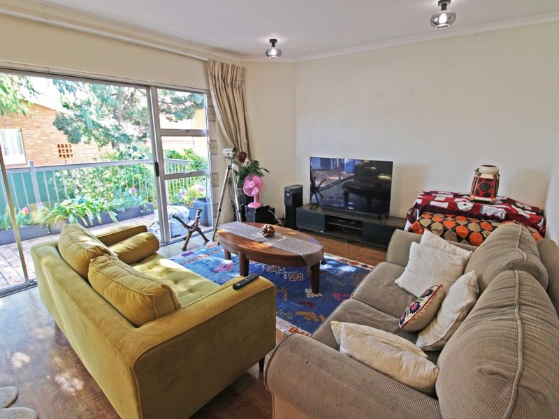 A comfortable living room featuring laminate flooring and a large sliding glass door that provides access to a private balcony.