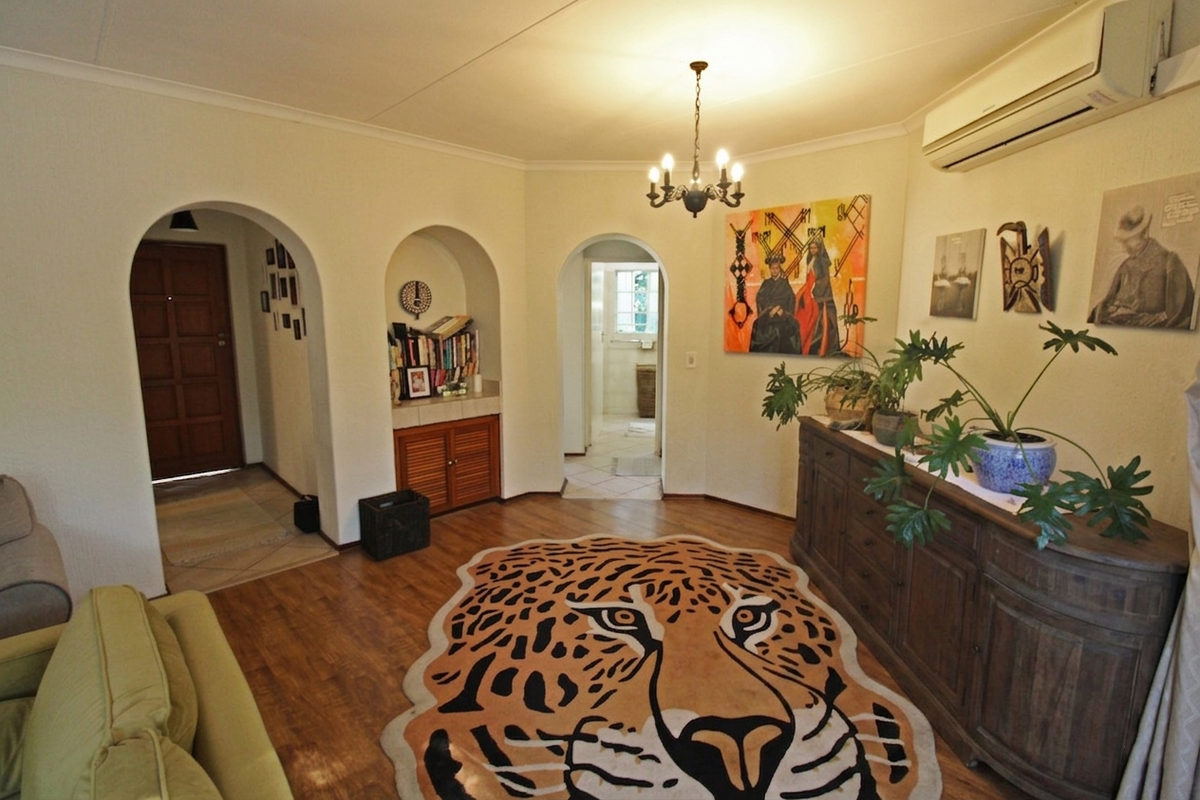 A well-maintained living area featuring distinctive arched doorways, built-in cabinetry, laminate flooring, and a wall-mounted split-system air conditioner.