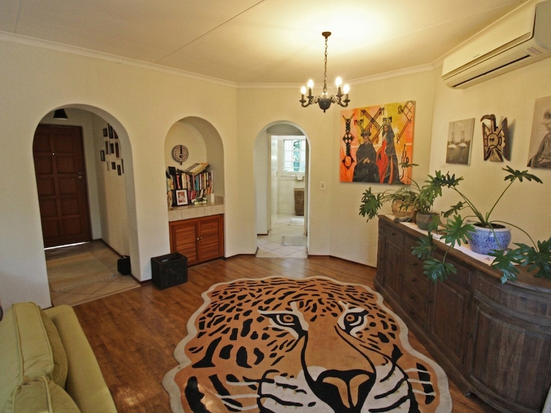 A well-maintained living area featuring distinctive arched doorways, built-in cabinetry, laminate flooring, and a wall-mounted split-system air conditioner.
