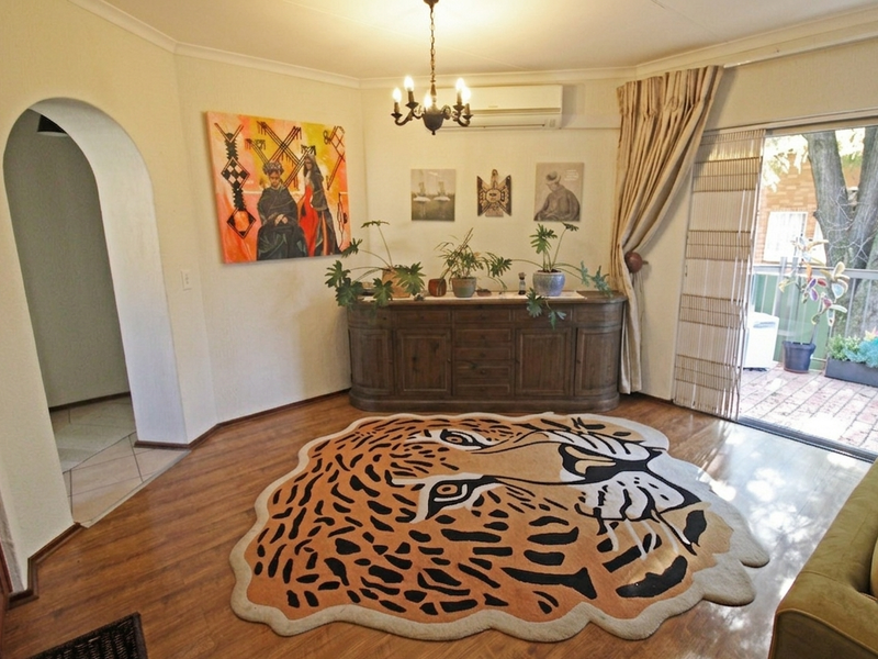 A living room featuring laminate flooring, an arched entryway, and a sliding glass door providing access to an outdoor patio area.