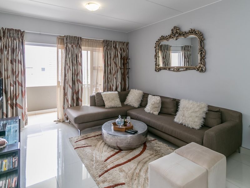 A bright and well-maintained living room featuring tiled flooring and a sliding glass door providing access to an outdoor balcony area.
