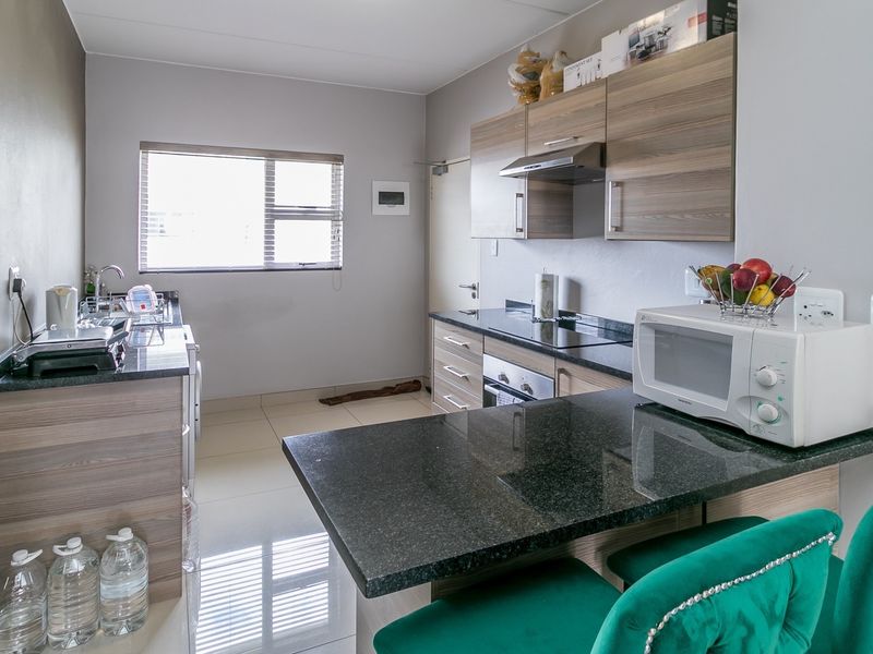 Modern kitchen featuring granite countertops, built-in cabinetry, stainless steel appliances, and tiled flooring, offering a functional and well-maintained cooking space.