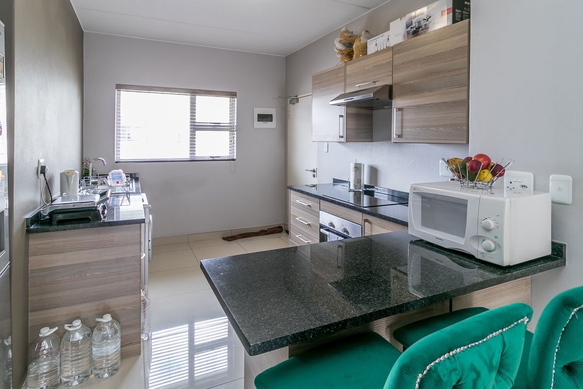 Modern kitchen featuring granite countertops, built-in cabinetry, stainless steel appliances, and tiled flooring, offering a functional and well-maintained cooking space.