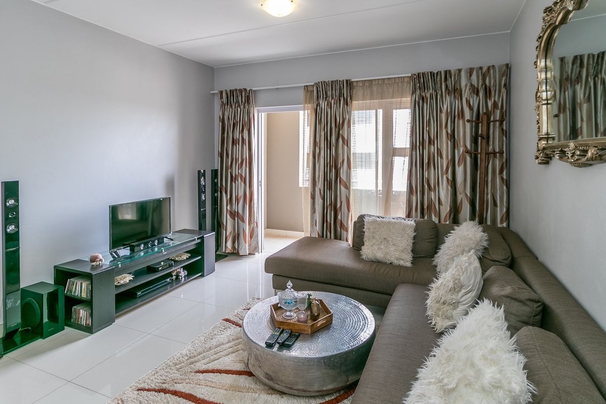 A well-maintained living room featuring polished tile flooring and a sliding glass door providing access to an outdoor balcony area.