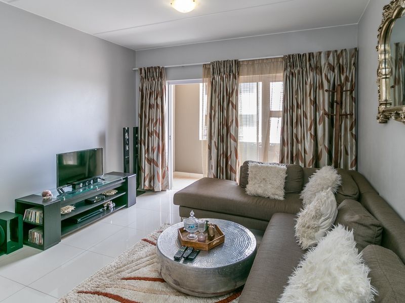 A well-maintained living room featuring polished tile flooring and a sliding glass door providing access to an outdoor balcony area.