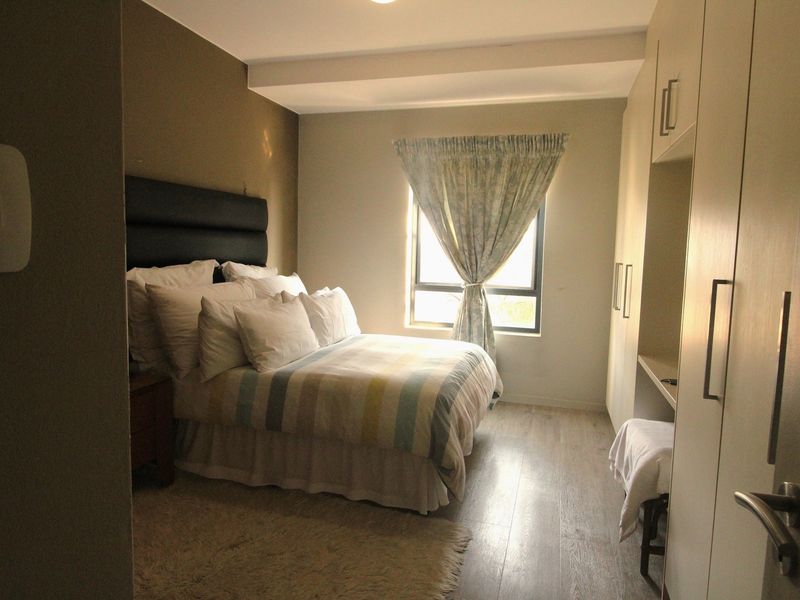 A well-lit bedroom featuring laminate flooring and ample built-in cupboard storage space.