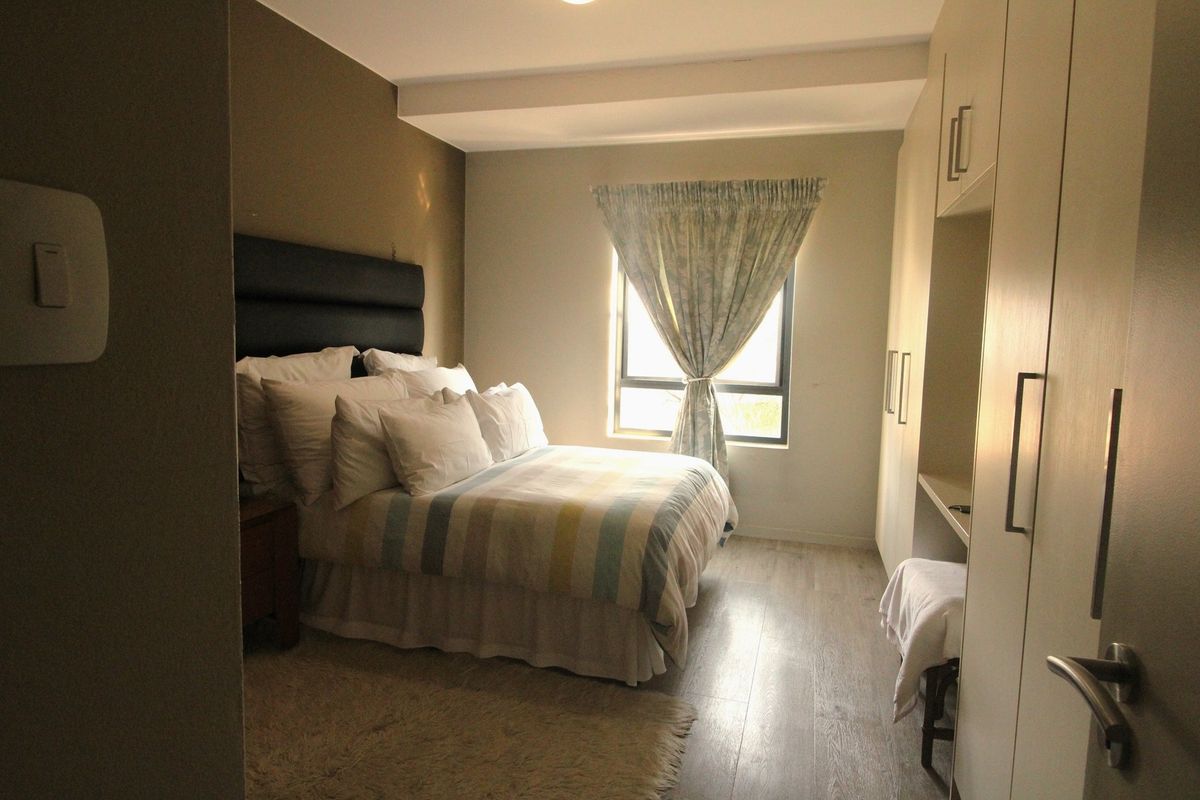 A well-lit bedroom featuring laminate flooring and ample built-in cupboard storage space.