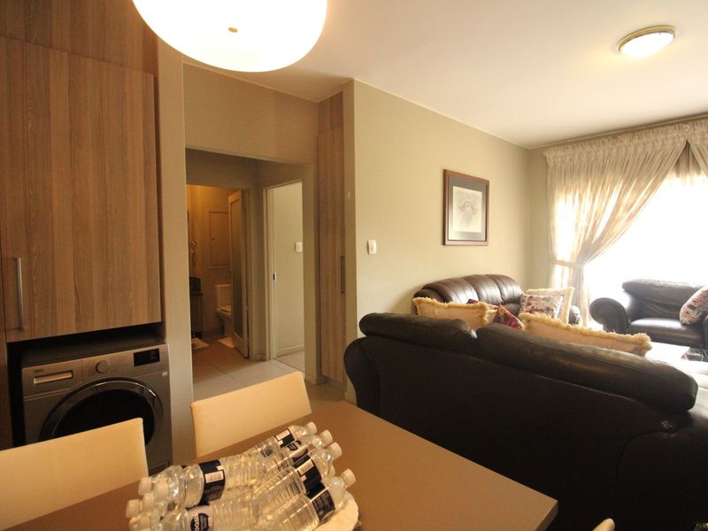 Open plan living area featuring built-in cabinetry with integrated laundry space, neutral wall finishes, and access to adjacent rooms.