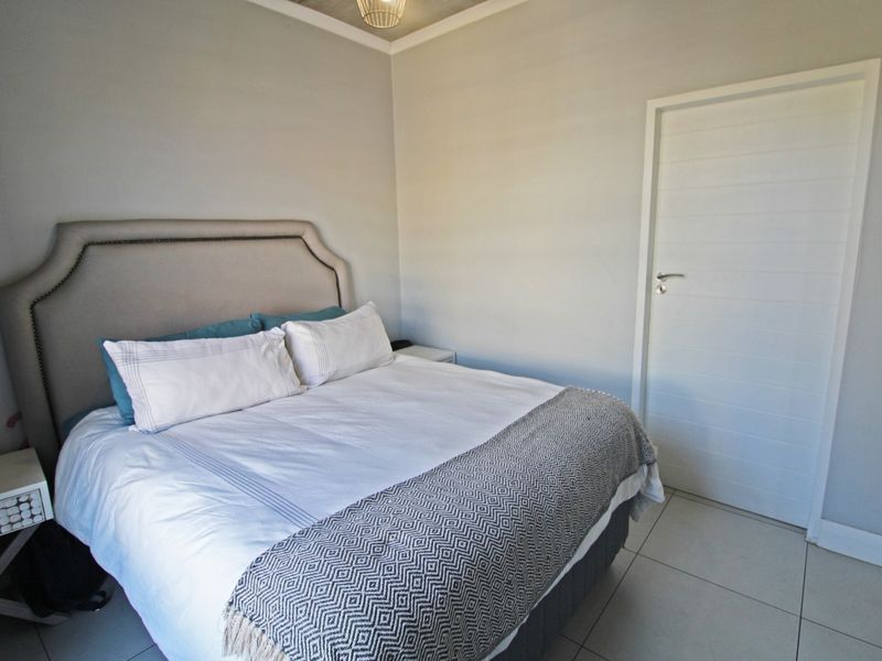 A well-maintained bedroom featuring neutral wall tones, tiled flooring, and a modern internal door.