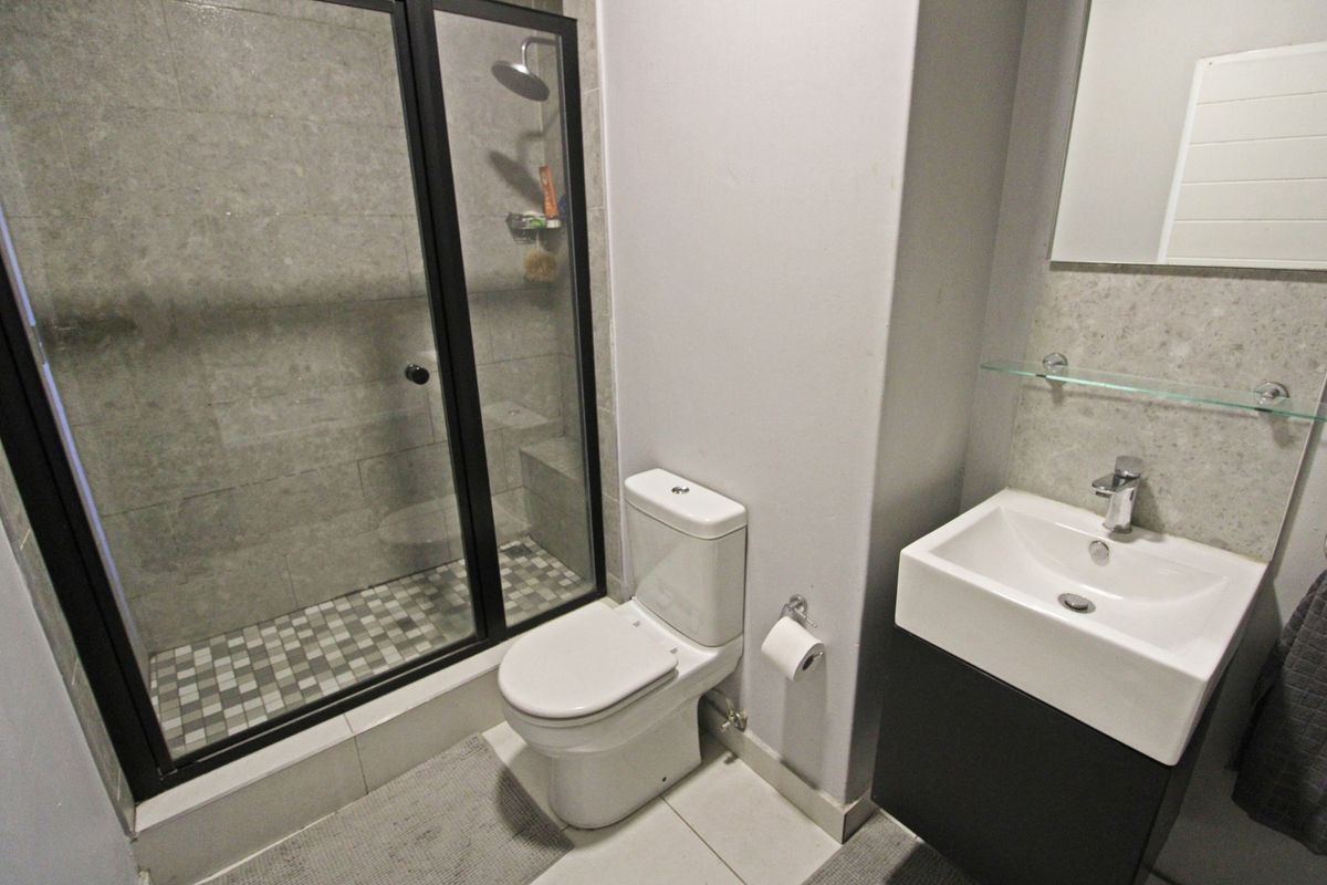 Modern bathroom featuring a walk-in shower with glass enclosure, contemporary vanity basin, and neutral tiled finishes throughout.