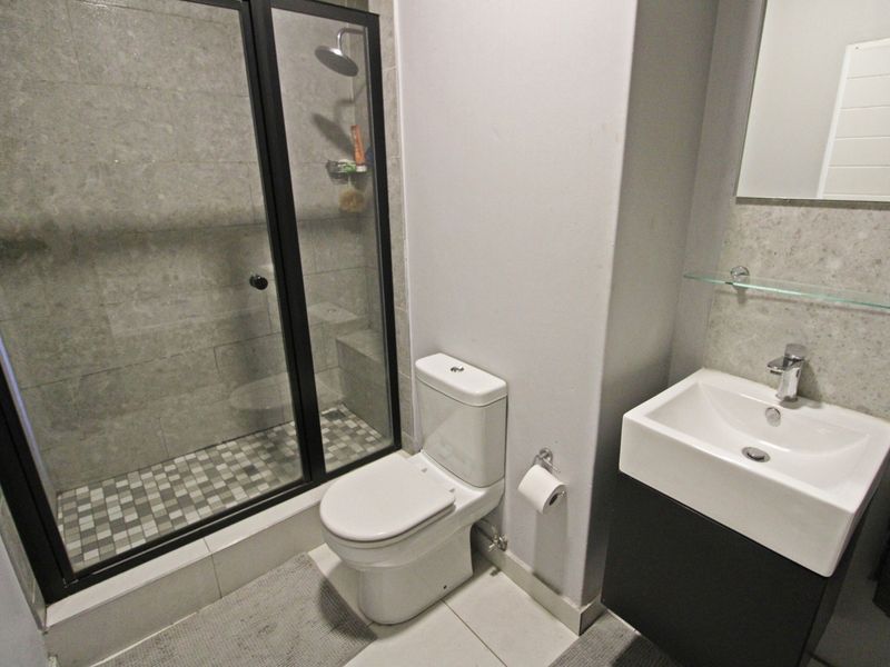 Modern bathroom featuring a walk-in shower with glass enclosure, contemporary vanity basin, and neutral tiled finishes throughout.