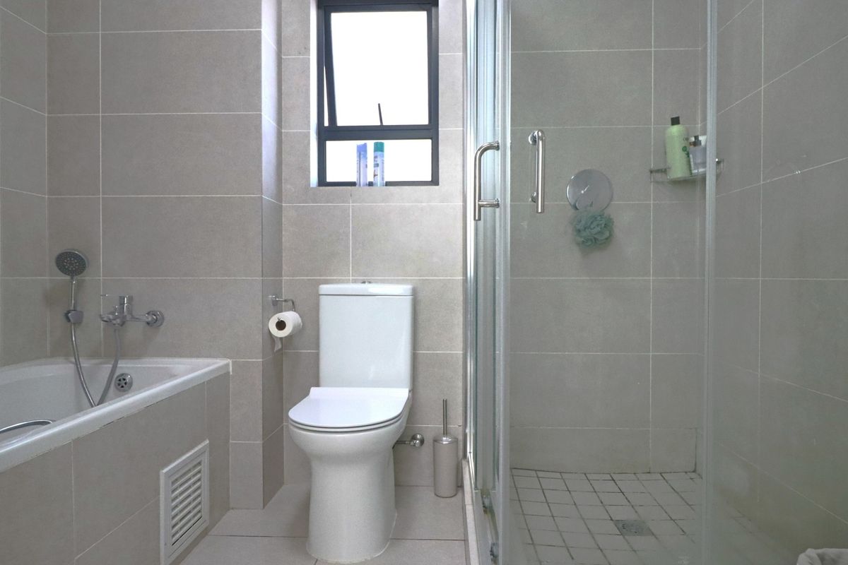 A modern bathroom featuring a bathtub, separate shower enclosure, and toilet with neutral wall and floor tiling.