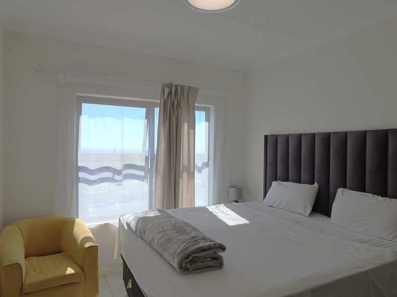 A bright bedroom featuring a large sliding glass door that provides natural light and access to an outdoor area.