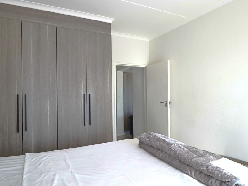 A well-maintained bedroom featuring modern grey built-in cupboards and classic cove cornicing, offering a clean and functional living space.