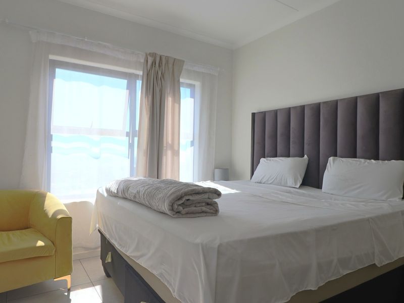 A bright bedroom featuring tiled flooring and a large window that allows for ample natural light.