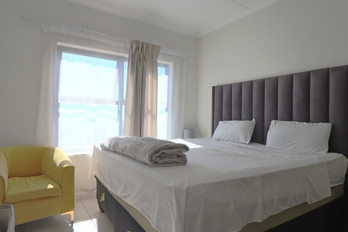 A bright bedroom featuring tiled flooring and a large window that allows for ample natural light.