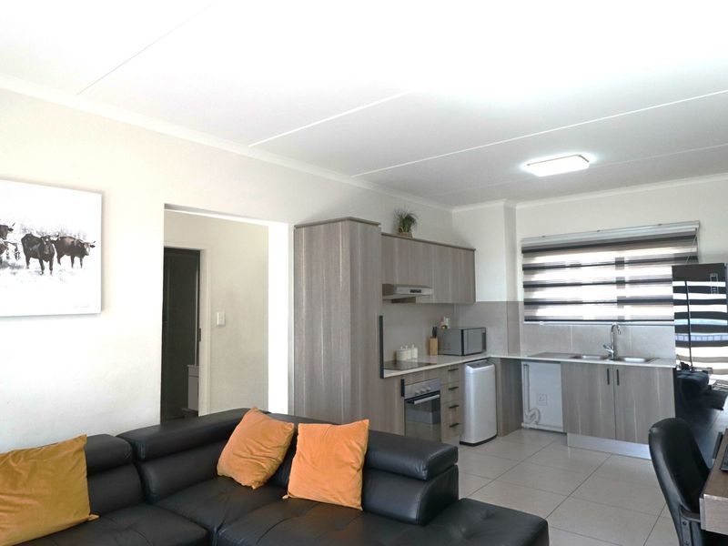 Open-plan living area featuring a modern kitchen with built-in cabinetry, integrated oven, extractor fan, and tiled flooring throughout.