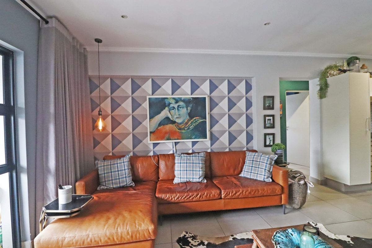 A well-lit living room featuring tiled flooring, recessed downlighting, and a decorative feature wall, creating a comfortable and modern living space.