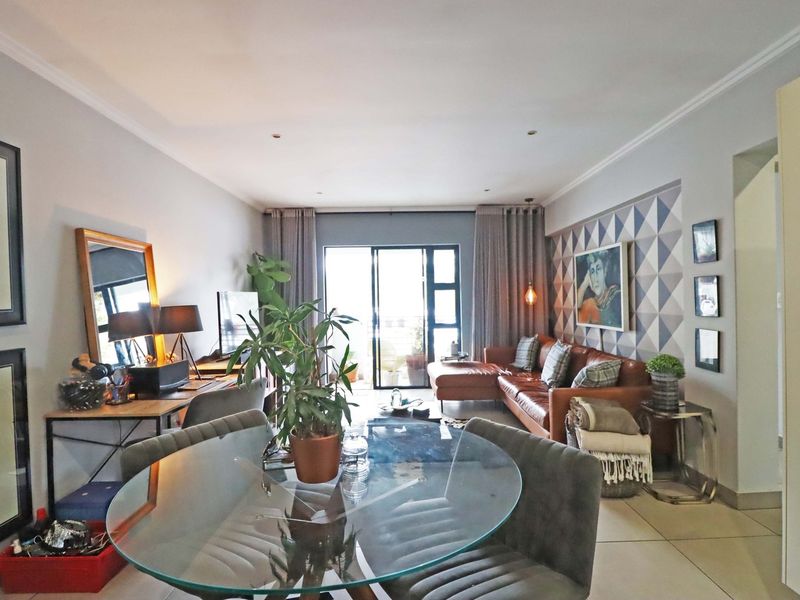 An open-plan living and dining area featuring tiled flooring, recessed lighting, and a sliding glass door leading to an outdoor space.