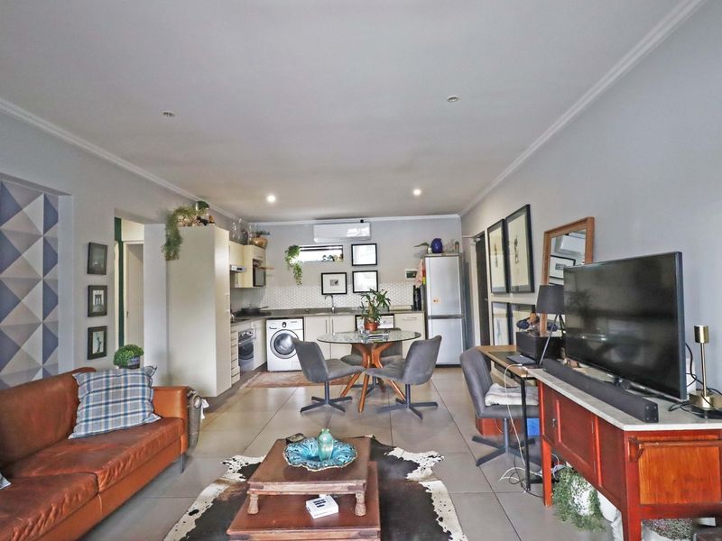 An open-plan living and kitchen area featuring tiled flooring, modern cabinetry, and a split-system air conditioner, creating a functional and cohesive living space.