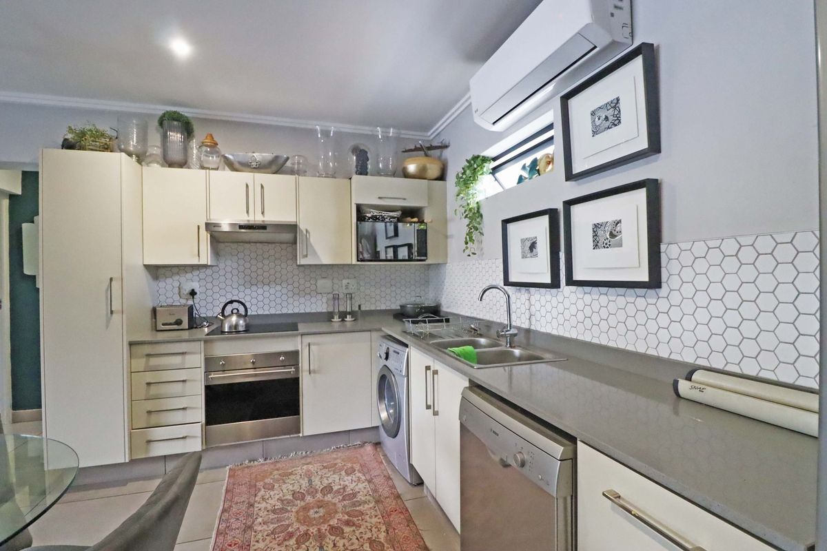 Modern kitchen featuring stone countertops, hexagonal tiled backsplash, built-in oven, hob, extractor fan, and integrated appliances including a dishwasher and washing machine.