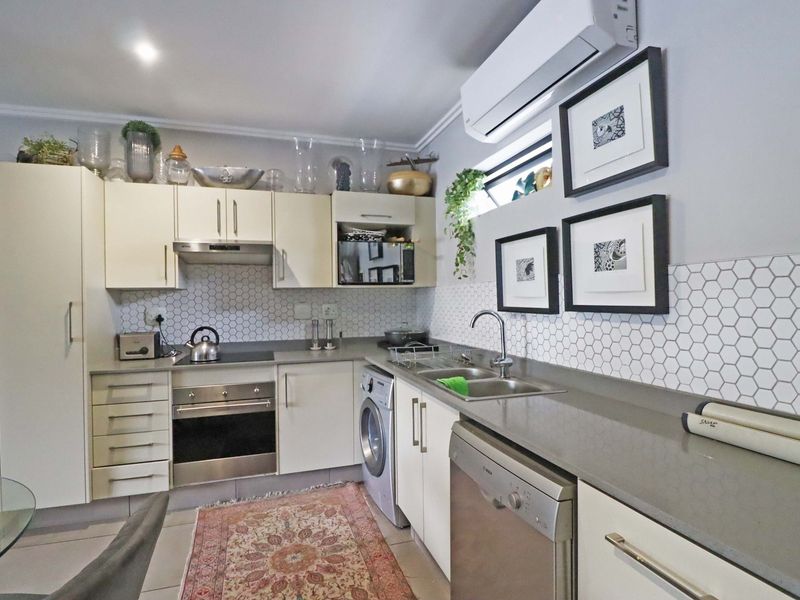Modern kitchen featuring stone countertops, hexagonal tiled backsplash, built-in oven, hob, extractor fan, and integrated appliances including a dishwasher and washing machine.